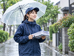 雨の日に傘を差しながらチラシを持つ配布スタッフのイメージ
