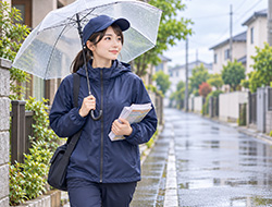 小雨の住宅街で傘を差して歩く配布スタッフ