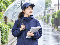 透明な傘とレインウェアで雨対策をする配布スタッフのイメージ