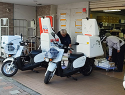 配布拠点でBOX付きバイクにチラシを準備している様子