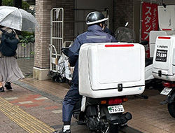 BOX付きバイクで配布に向かうケイ・アンド・パートナーズのスタッフ