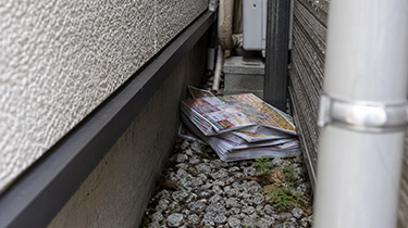 住宅と住宅の間にチラシの束が残されているイメージ