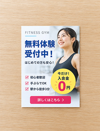 ハガキサイズの架空のフィットネスジム無料体験チラシ。木目の上に小さく置かれた広告例